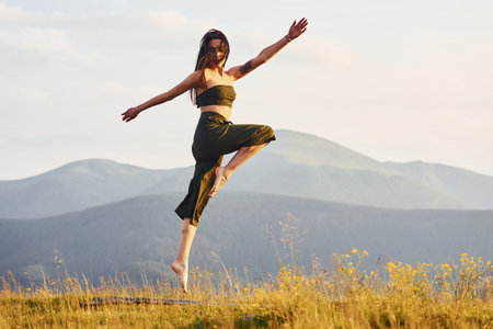 Beautiful young woman doing yoga exercises. Majestic Carpathian Mountains. Beautiful landscape of untouched natureの写真素材