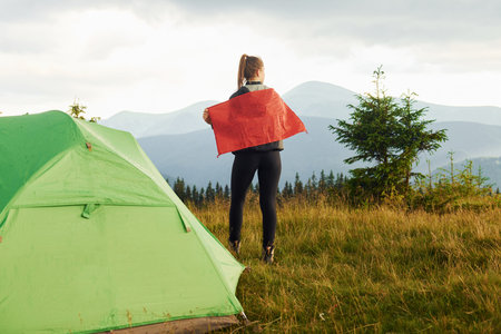 Woman standing with red flag. Majestic Carpathian Mountains. Beautiful landscape of untouched natureの写真素材