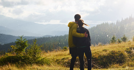 Girlfriend with her boyfriend embracing each other. Majestic Carpathian Mountains. Beautiful landscape of untouched natureの写真素材