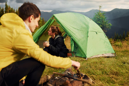 Guy making campfire. Girlfriend just woke up. Majestic Carpathian Mountains. Beautiful landscape of untouched natureの写真素材