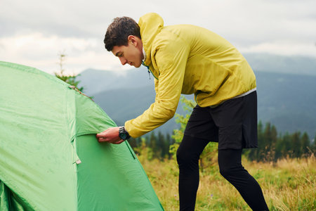 Guy works with his tent. Majestic Carpathian Mountains. Beautiful landscape of untouched natureの写真素材