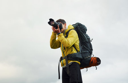 Young male photographer with his professional camera taking pictures of beautiful natureの写真素材