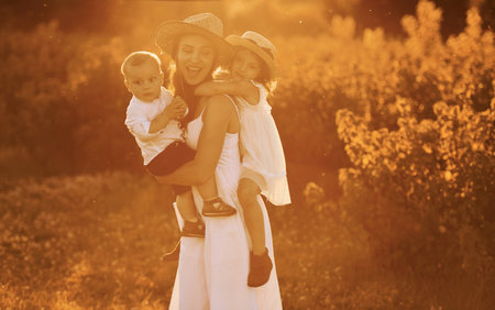 Happy family of mother, little son and daughter spending free time on the field at sunny day time of summerの写真素材