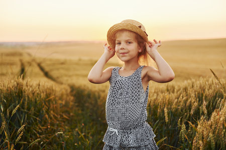 Little girl standing on the agricultural field at evening time. Conception of summer free timeの写真素材