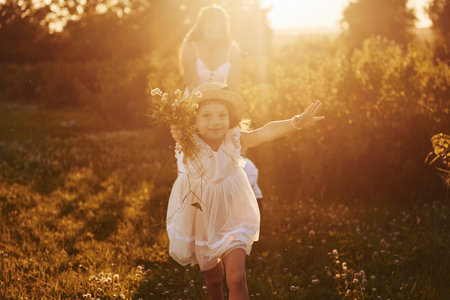 Beautiful lightbeam. Mother with boy and girl spending free time on the field at sunny day time of summerの写真素材