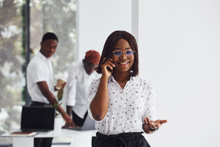 Portrait of woman in glasses. Group of african american business people working in office togetherの写真素材