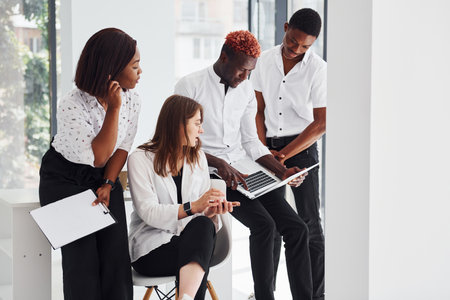 Busy and holding laptop and notepad. Group of african american business people working in office togetherの写真素材