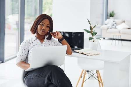 Young african american woman in formal clothes is in the office with laptopの写真素材