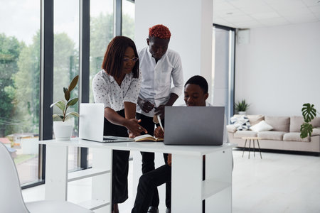 Using same laptop for the project. Group of african american business people working in office togetherの写真素材