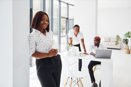 Beautiful woman standing in front of colleagues. Group of african american business people working in office togetherの写真素材