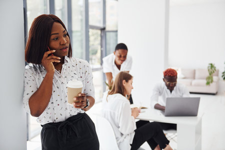 Beautiful woman standing in front of colleagues. Group of african american business people working in office togetherの写真素材