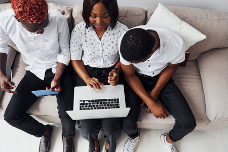 Comfortable sofa. Using laptop. Group of african american business people working when sitting togetherの写真素材