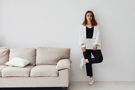 Young european girl in formal clothes is indoors with laptopの写真素材