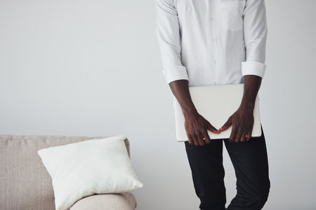 Young african american man in formal clothes indoors with laptop in handsの写真素材