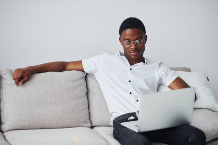 Young african american man in formal clothes indoors with laptop in handsの写真素材
