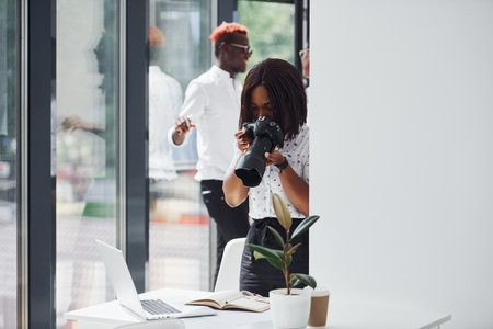 Woman testing camera. Group of african american business people working in office togetherの写真素材