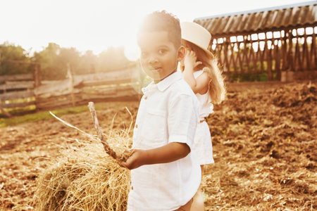 Cute little african american boy with european girl is on the farmの写真素材