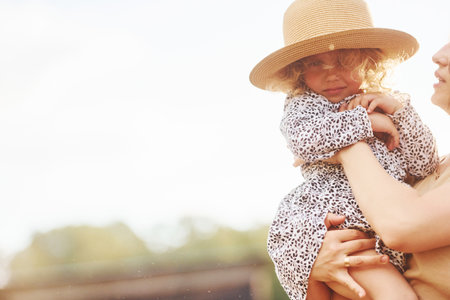Young mother with her daughter is on the farm at summertime