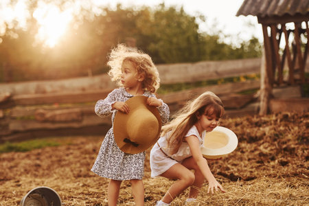 Two little girls together on the farm at summertime having weekendの写真素材