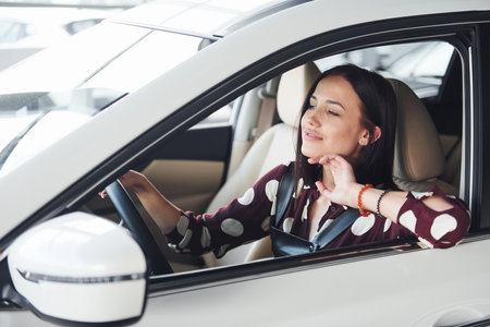 Side view of beautiful young brunette that inside of modern automobile. Riding carの写真素材