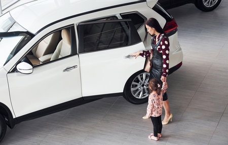 Mother with her daughter walking together near modern automobile indoorsの写真素材