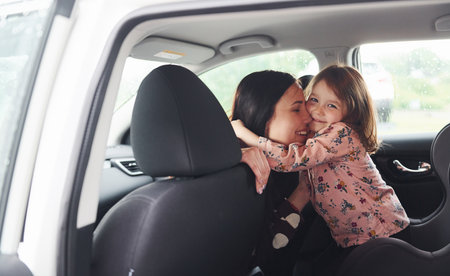 Embracing each other. Mother with her daughter inside of modern automobile togetherの写真素材