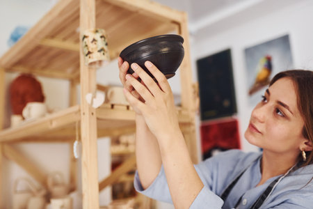 Job is done. Young female ceramist indoors with finished handmade clay product. Conception of potteryの写真素材