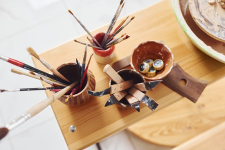 Top view of brushes and other pottery tools that is on the wooden tableの写真素材