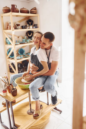 With her boyfriend or husband. Young female ceramist have a works indoors with handmade clay...