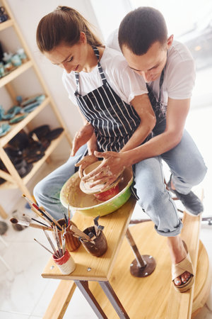 With her boyfriend or husband. Young female ceramist have a works indoors with handmade clay product. Conception of potteryの写真素材