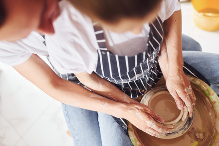 With her boyfriend or husband. Close up view of young female ceramist that indoors with handmade...