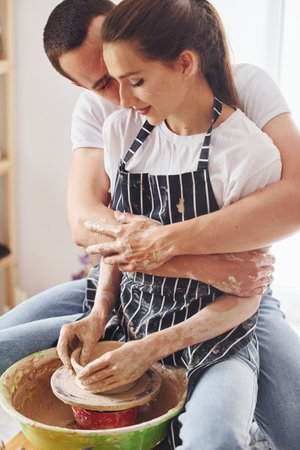 With her boyfriend or husband. Young female ceramist have a works indoors with handmade clay product. Conception of potteryの写真素材