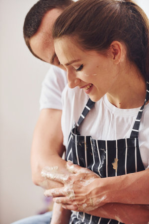 With her boyfriend or husband. Young female ceramist indoors with handmade clay product. Conception of potteryの写真素材