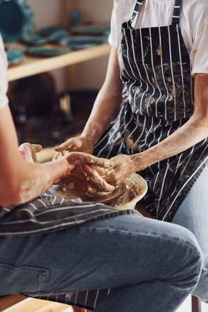 With her boyfriend or husband. Close up view of young female ceramist that indoors with handmade clay product. Conception of potteryの写真素材
