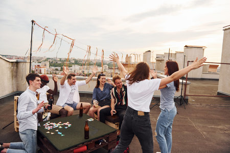 Group of young people in casual clothes have a party at rooftop together at daytime