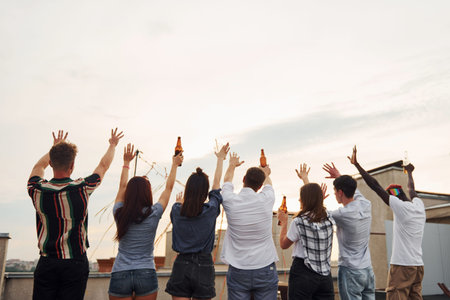 Standing high and looking at the cloudy sky. Group of young people in casual clothes have a party at...