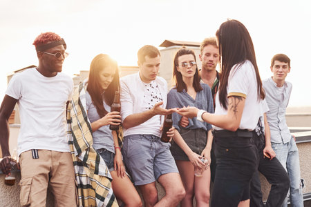 Cloudy weather. Group of young people in casual clothes have a party at rooftop together at daytimeの写真素材