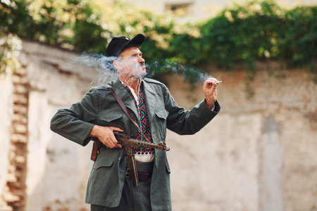 TERNOPIL, UKRAINE - June 2020 UPA Ukrainian Insurgent Army movie filming. Pictures of backstage. Old soldier with weapon smokingのeditorial素材