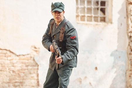 TERNOPIL, UKRAINE - June 2020 UPA Ukrainian Insurgent Army movie filming. Pictures of backstage. Young soldier with weapon near old buildingのeditorial素材