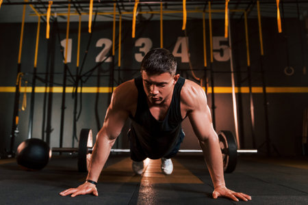 Strong man in sportive clothes doing push-ups in the gym
