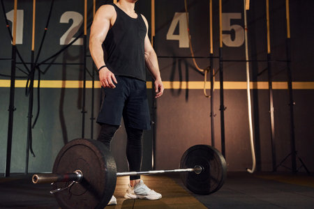 Strong man in sportive clothes lifting barbell in the gymの写真素材