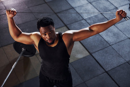 Top view. Barbell on the floor. Strong african american man in sportive clothes have workout day in the gymの写真素材
