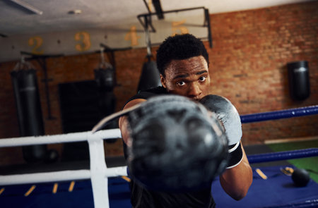 Strong african american boxer in sportive clothes have practice in the gymの写真素材