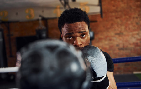 Strong african american boxer in sportive clothes have practice in the gymの写真素材