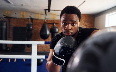 Strong african american boxer in sportive clothes have practice in the gym