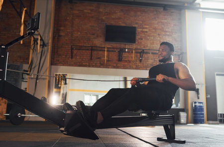 Strong african american man in sportive clothes have workout day in the gym by using equipment