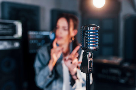 Close up view of microphone. Young beautiful female performer rehearsing in a recording studioの写真素材
