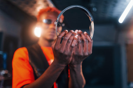 Young african american performer standing in a recording studio and holding headphonesの写真素材