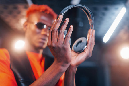 Young african american performer standing in a recording studio and holding headphonesの写真素材
