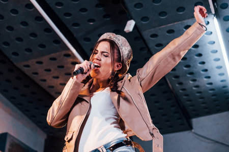 Young beautiful female performer rehearsing in a recording studio